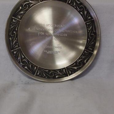 Silberne Plakette mit gravierter Inschrift: „4. Altherrn-Dartturnier für Sportkegler, 1979, 1. Preis“. Ornamental verzierter Rand.