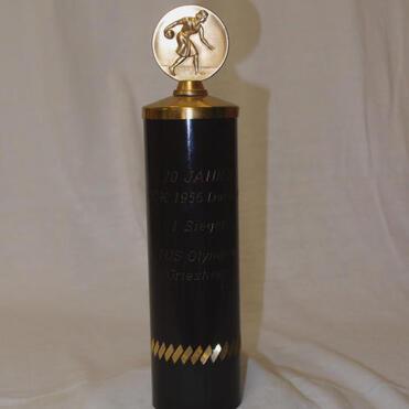 Schwarz-goldener Pokal mit einer Medaille oben, graviert mit „1. Platz, TUS Olympiad Gresheim, 20 Jahre“ und sportlicher Figur.