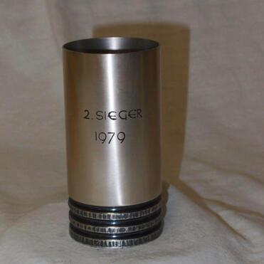 Edelstahlpokal mit der Gravur „2. SIEGER 1979“ auf einer hellen Stoffoberfläche.