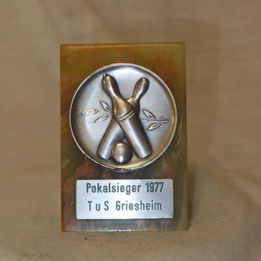 Pokal mit eingearbeitetem Silbermedaille des TuS Griesheim, gekennzeichnet mit „Pokalsieger 1977“.