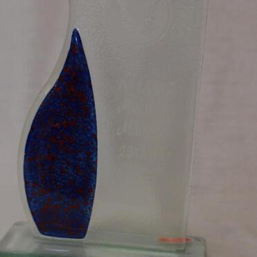 Durchsichtige Glastrophäe mit blauer Füllung und eingravierter Schrift auf einem stabilen Sockel.