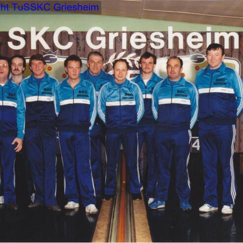 Gruppe von zehn Männern in Trainingsanzügen vor einer Kegelbahn, mit dem Schriftzug „SKC Griesheim“ im Hintergrund.