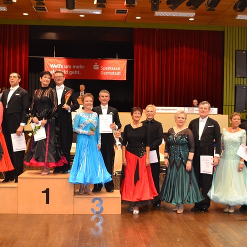 T&auml;nzerpaare stehen auf dem Siegertreppchen bei einem Tanzwettbewerb in festlicher Kleidung.