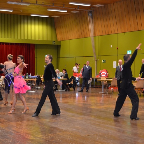 Tanzpaar in farbenfrohen Kost&uuml;men auf einer Tanzfl&auml;che beim Wettbewerb in einer festlich dekorierten Halle.