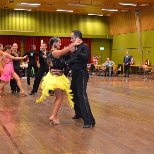 Tanzpaare f&uuml;hren lateinamerikanische T&auml;nze auf einer Wettbewerbsebene in einem festlichen Saal aus.