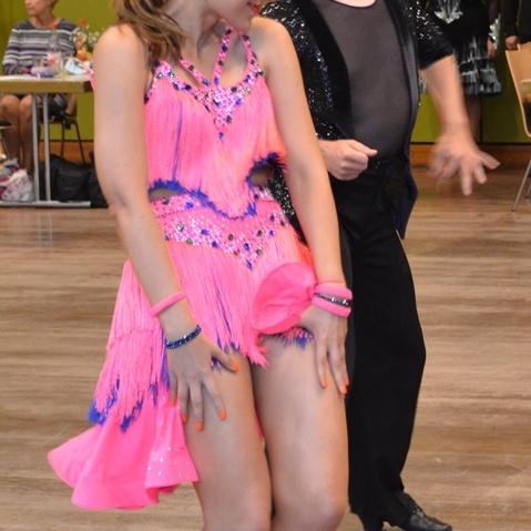 Tanzpaar in Tanzkleidung w&auml;hrend eines Wettbewerbs auf einer Tanzfl&auml;che. Der Mann l&auml;chelt, die Frau zeigt eine dynamische Pose.