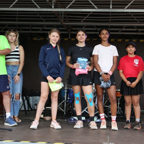 Sechs Personen stehen auf einer B&uuml;hne, w&auml;hrend eine Person ein Mikrofon h&auml;lt. Sie halten Preise in den H&auml;nden.