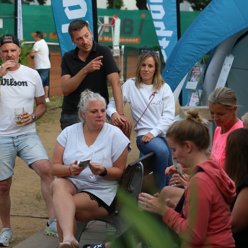 Eine Gruppe von f&uuml;nf Personen unterh&auml;lt sich entspannt auf einer Veranstaltung im Freien, umgeben von Natur.