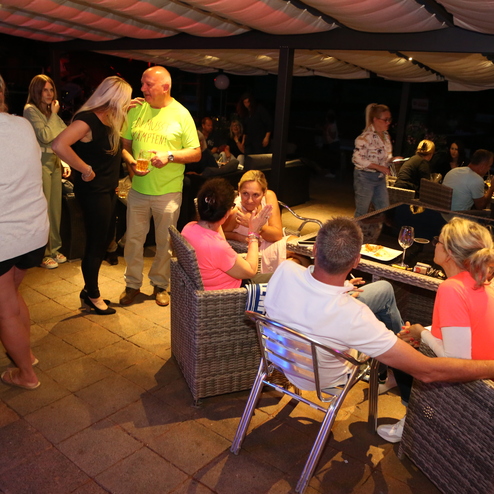 Gesellige Atmosph&auml;re in einem Au&szlig;enbereich mit mehreren G&auml;sten, die in Lounge-Sesseln sitzen und miteinander sprechen.