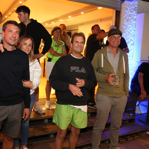 Gruppe von f&uuml;nf Personen, die l&auml;chelnd auf einer Treppe stehen, in einem beleuchteten Aufenthaltsraum.