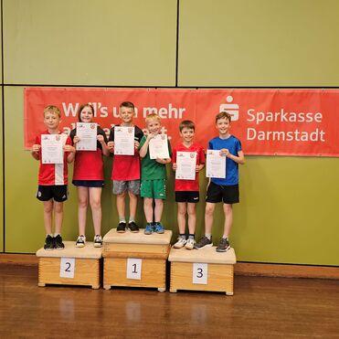 Sechs Kinder stehen auf einem Podest und halten Urkunden, vor einem Banner der Sparkasse Darmstadt.