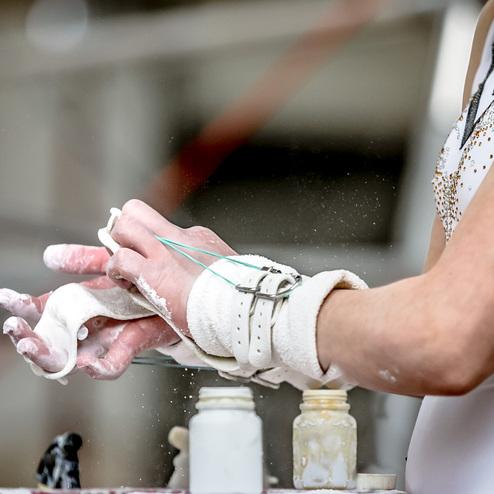 Nahaufnahme einer Hand mit Magnesia-Puder, während eine andere Hand eine weiße Tuchstück in der Nähe hält.