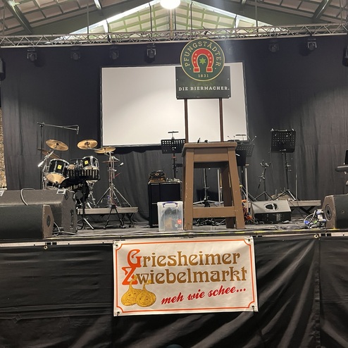 B&uuml;hne mit Musikinstrumenten, Lautsprechern und Banner f&uuml;r den Griesheimer Zwiebelsmarkt in einem festlichen Ambiente.