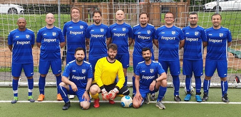Mannschaftsfoto einer Fußballmannschaft in blauen Trikots vor einem Tor auf einem Kunstrasenplatz.