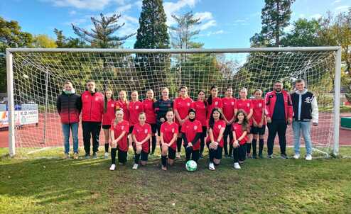 Mannschaftsfoto einer Jugendfußballmannschaft in roten Trikots vor einem Tor auf einem Sportplatz.