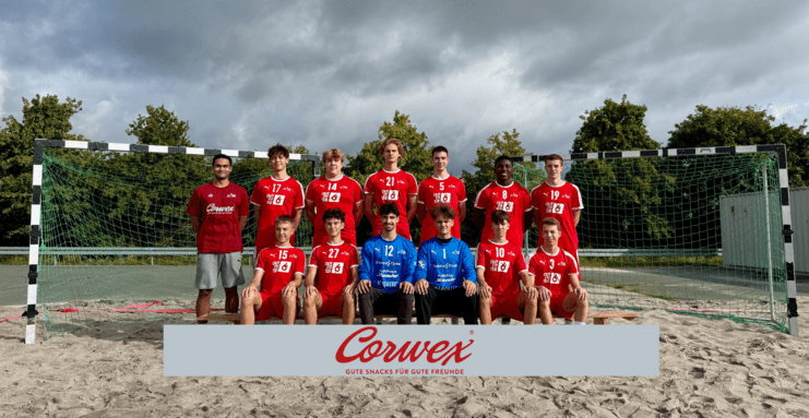 Gruppe von Fußballspielern in Rot-weiß, stehend und sitzend vor einem Tor auf Sandplatz, mit Logo im Vordergrund.