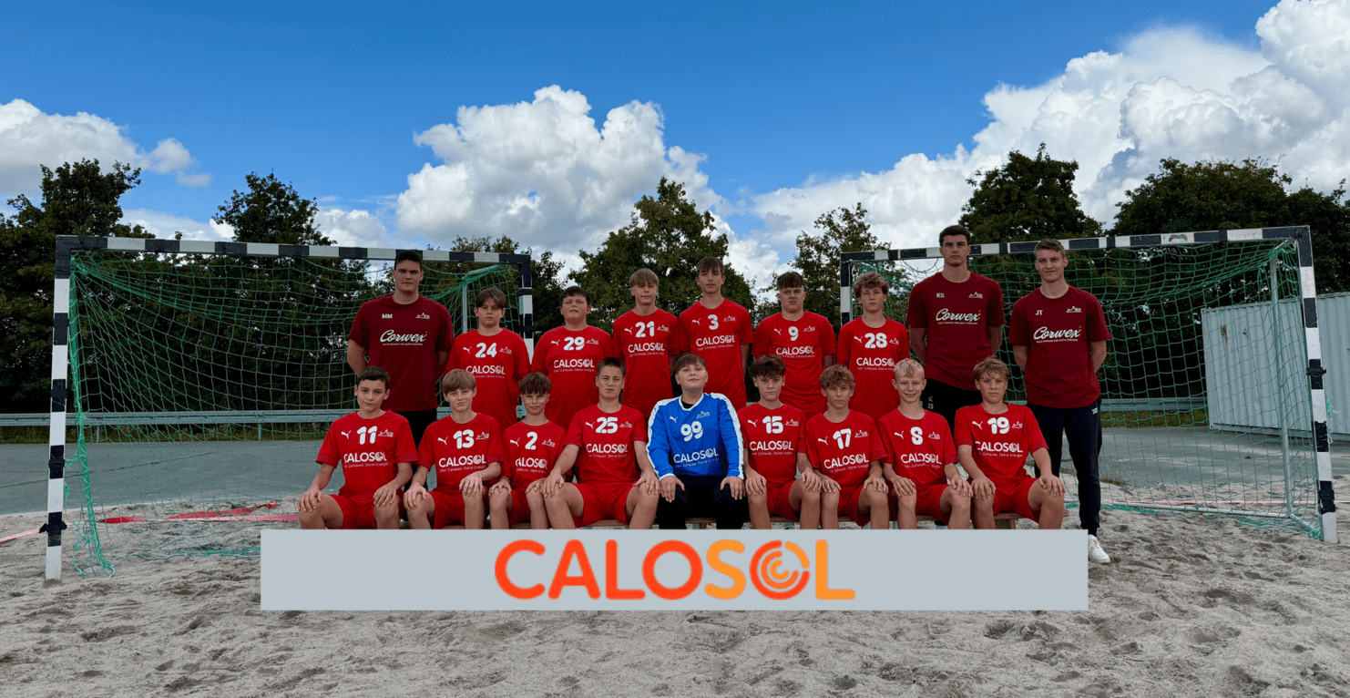 Gruppenfoto einer Jugend-Handballmannschaft in roten Trikots vor einem Tor auf einem Sandplatz.