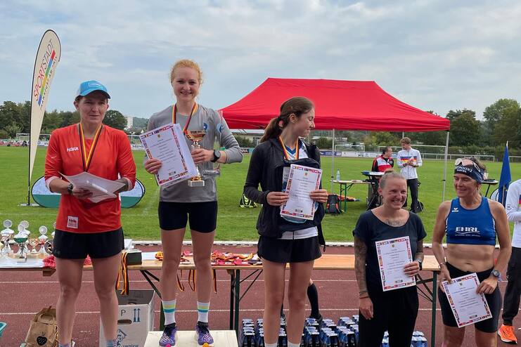F&uuml;nf Sportlerinnen auf dem Siegertreppchen mit Medaillen und Urkunden bei einer Leichtathletikveranstaltung.