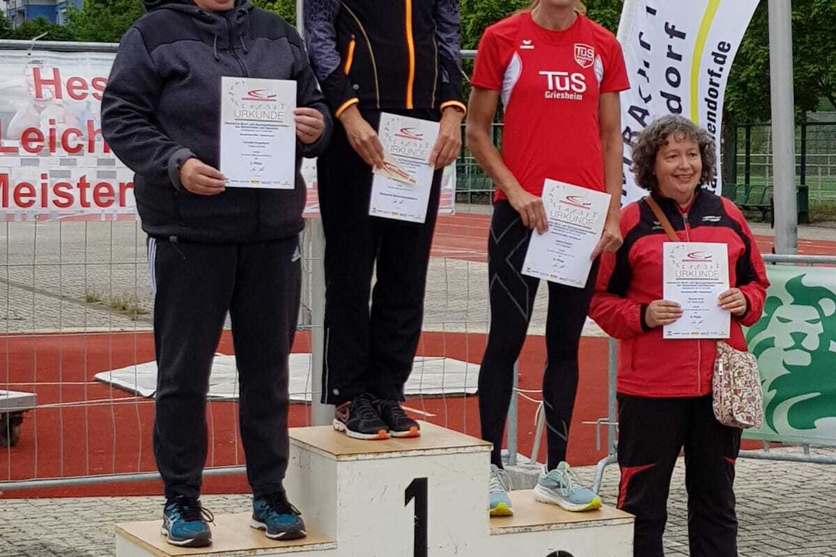 Vier Frauen stehen auf einem Siegerpodest, jede hält eine Urkunde, bei einem Leichtathletik-Wettkampf in einem Stadion.