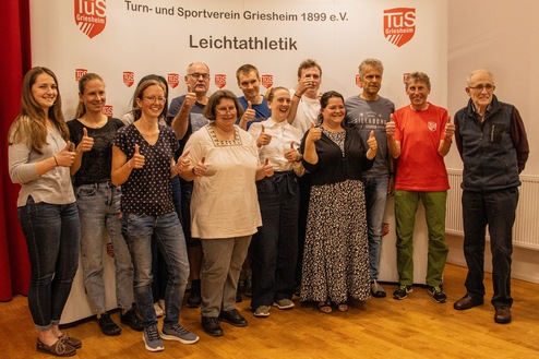 Gruppenzsammenkunft von Teilnehmern der Leichtathletikabteilung des TUS Griesheim, alle zeigen Daumen hoch.