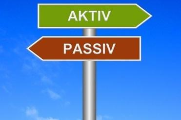 Schild mit den Richtungen „AKTIV“ in Grün und „PASSIV“ in Braun vor einem klaren blauen Himmel.