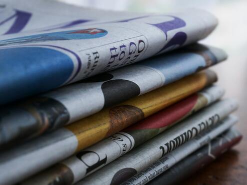 Nahaufnahme eines gestapelten Zeitungsb&uuml;ndels mit unterschiedlichen Titelseiten und Farben.