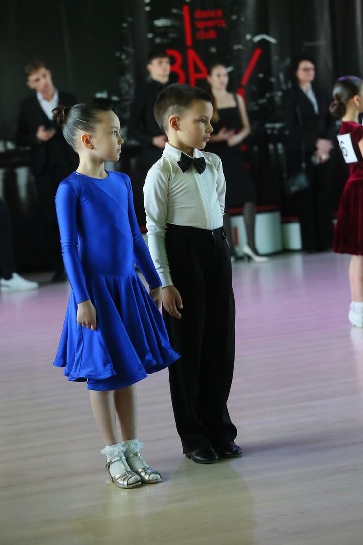 Zwei Kinder stehen nebeneinander, das Mädchen in einem blauen Kleid und der Junge in Anzug mit Fliege.