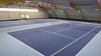 Man sieht eine neu renovierte Tennishalle von innen, 2 Plätze, blauer Teppich, bunte Balken