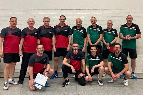 Gruppenshot von zehn Tischtennisspielern in roten und grünen Trikots, posierend vor einer weißen Wand in Sporthalle.
