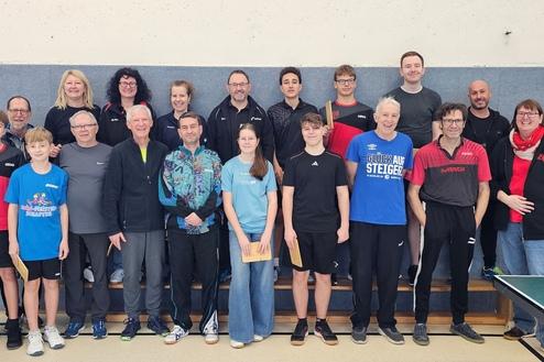 Gruppenfoto von Tischtennisspielern, die auf einer Bühne in Sportbekleidung stehen, lächelnd und posierend.