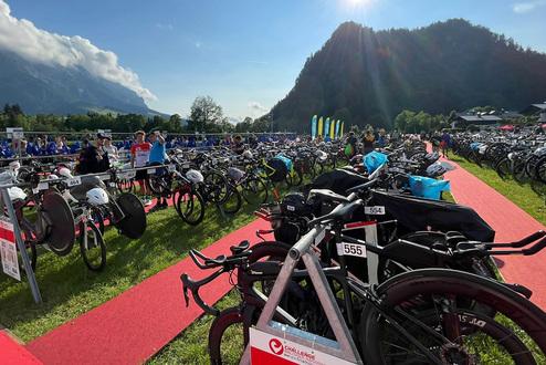 Zahlreiche Fahrräder auf einem Wettkampfgelände, umgeben von Bergen und bei strahlendem Sonnenschein.
