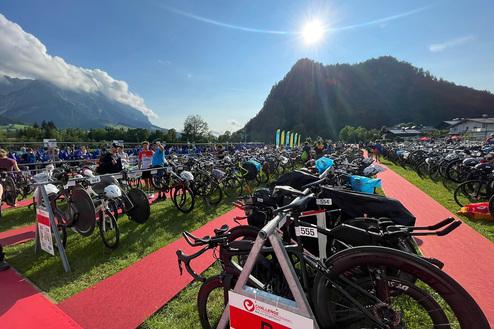 Zahlreiche Fahrräder auf einem Wettkampfgelände, umgeben von Bergen und bei strahlendem Sonnenschein.