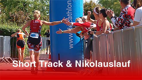 Läuferin überquert das Ziel beim Short Track und Nikolauslauf, umgeben von jubelnden Zuschauern.