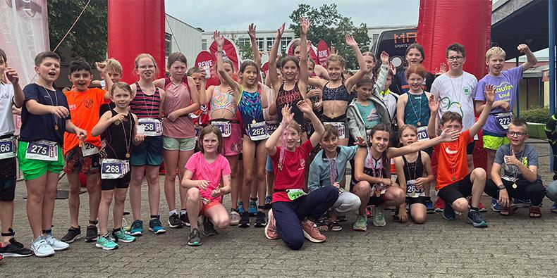 Gruppe von Kindern in Sportkleidung, die stolz nach einem Wettkampf posieren, einige halten Medaillen in den H&auml;nden.