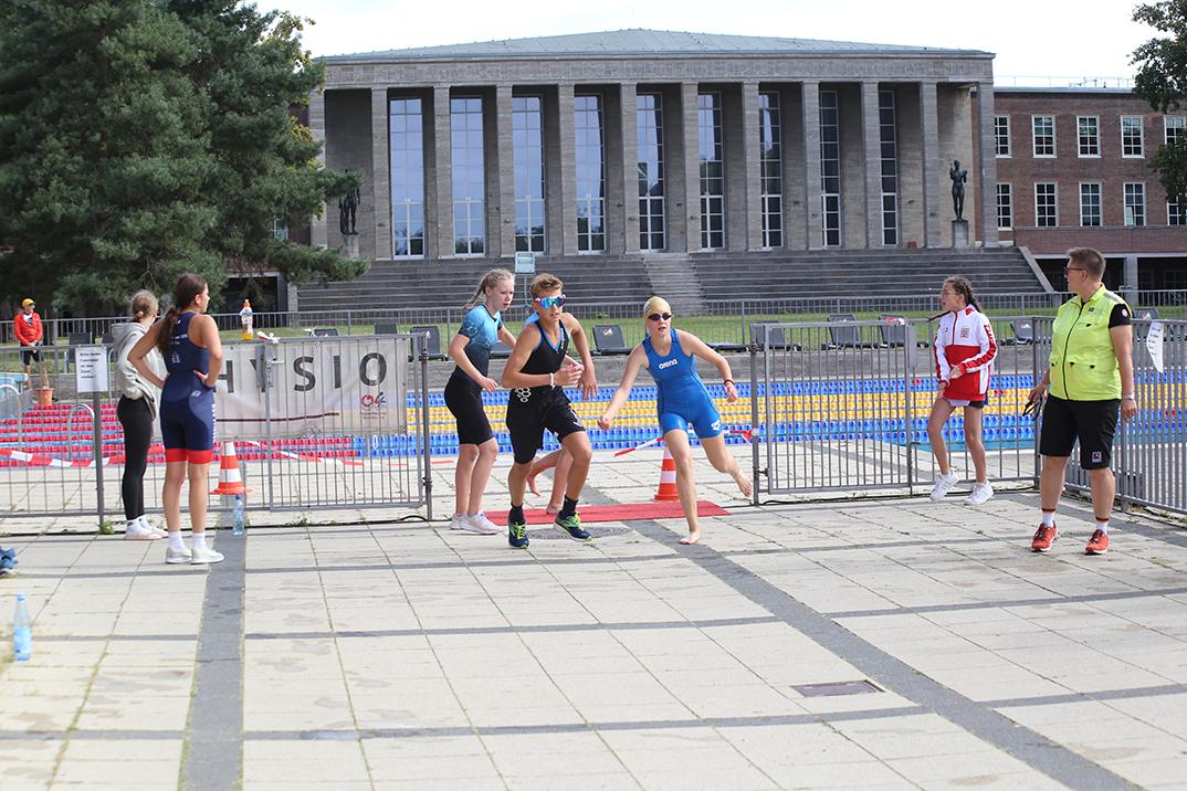 Sportliche Athleten starten in einem Triathlon-Event vor dem Hintergrund eines historischen Gebäudes.