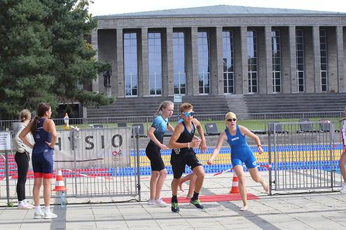 Sportliche Athleten starten in einem Triathlon-Event vor dem Hintergrund eines historischen Gebäudes.