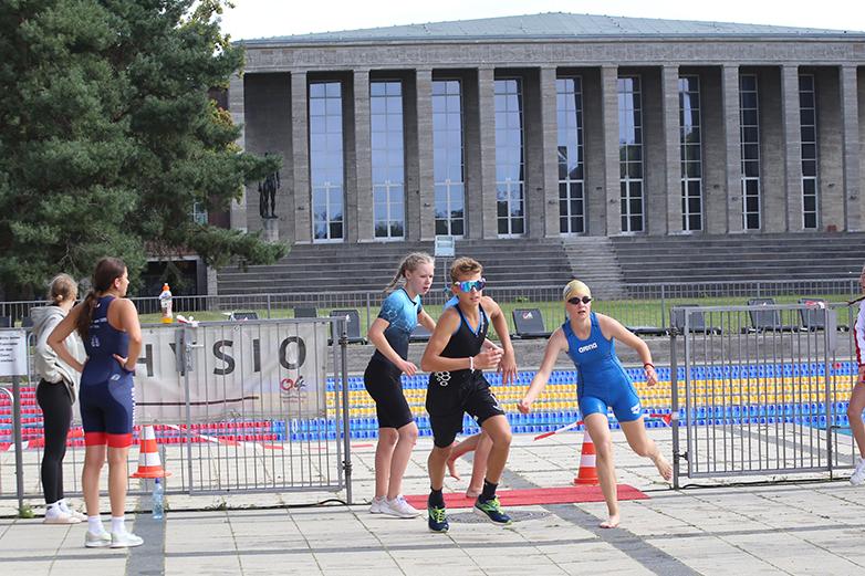 Sportliche Athleten starten in einem Triathlon-Event vor dem Hintergrund eines historischen Gebäudes.