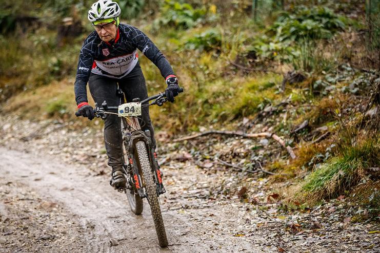 Mountainbiker auf einem schmalen, matschigen Pfad, tr&auml;gt die Nummer 94 und steuert geschickt um Hindernisse.