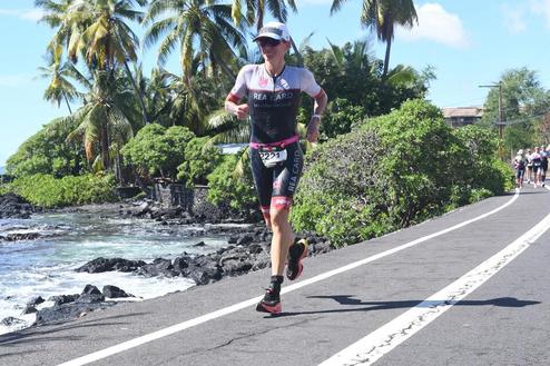 Athlet in sportlicher Kleidung joggt entlang einer Küstenstraße, umgeben von Palmen und dem Meer.