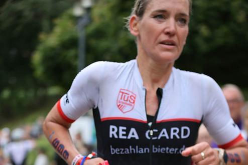 Sportlerin beim Laufwettbewerb, gekleidet in ein schwarzes Trikot mit roten Akzenten und der Startnummer 699.