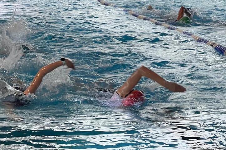 Schwimmerinnen im Wasser, die Wettkampfstarts im R&uuml;ckenschwimmen auf einer Bahn im Schwimmbecken ausf&uuml;hren.