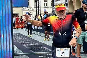 Ein älterer Mann in einem bunten Triathlonanzug läuft bei den Europe Triathlon Cross Championships ins Ziel.