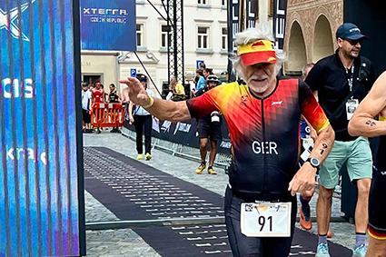 Ein älterer Mann in einem bunten Triathlonanzug läuft bei den Europe Triathlon Cross Championships ins Ziel.