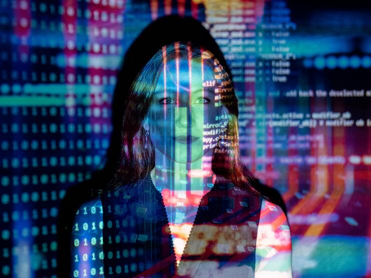 Frau mit langen Haaren, überlagert von bunten, digitalen Code-Mustern und binären Zahlen in einem dunklen Raum.